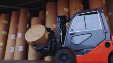 Forklift büyük bir rulo kağıt taşıyor. Bir forklift fabrikada kağıt taşıyor. Duvar kağıdı fabrikasında yükleyici.