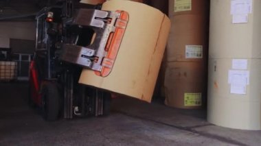 Forklift büyük bir rulo kağıt taşıyor. Bir forklift fabrikada kağıt taşıyor. Duvar kağıdı fabrikasında yükleyici.