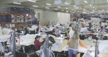 Bir terzi elbise fabrikasında çalışıyor. Tekstil üretimi. Çalışma süreci. Profesyonel ekipman dikiyorum..