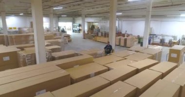 Fabrikada bitmiş ürünlerle dolu büyük bir depo. Fabrikada kutularla dolu bir depo. Büyük bir depodaki bir forklift kutuları taşır..