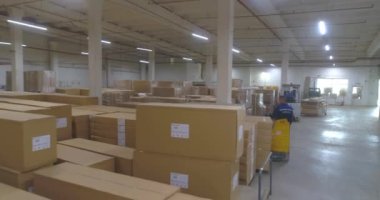 Fabrikada bitmiş ürünlerle dolu büyük bir depo. Fabrikada kutularla dolu bir depo. Büyük bir depodaki bir forklift kutuları taşır..