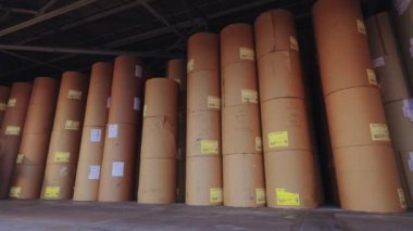 The forklift is carrying a large roll of paper. A forklift is carrying paper at the factory. Loader at the wallpaper factory.