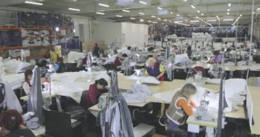 Büyük dikiş atölyesi. Terziler fabrikada kıyafet yaparlar. Giysi fabrikası. Kıyafet üretim atölyesi.