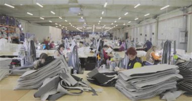 Birçok terzi bir giyim fabrikasında çalışır. Bir giyim fabrikasında çalışma süreci. Büyük dikiş atölyesi. Terziler fabrikada ürün yapar. Kumaş fabrikası.