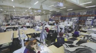 Birçok terzi bir giyim fabrikasında çalışır. Bir giyim fabrikasında çalışma süreci. Büyük dikiş atölyesi. Terziler fabrikada ürün yapar. Kumaş fabrikası.