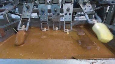 The chocolate drips nicely off the ice cream. Chocolate dripping from ice cream slow motion. Ice cream is dipped in chocolate at the factory.