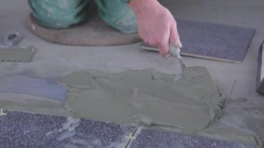 İnşaatçı çimento harcının üzerine fayanslar serer. İnşaat işçisi havan topu için yere fayans döşedi..