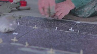 The builder lays tiles on the cement mortar. Construction worker laying tiles on the floor for mortar.