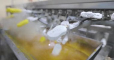 Ice cream is dipped into a container with fruit glaze. Colorful bright ice cream on the conveyor. Ice cream production.