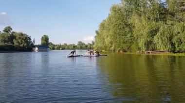 Girls do sports exercises on the sup board. Physical exercises on the sup board. Sports recreation on the river. Water sports.