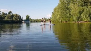 Girls do sports exercises on the sup board. Physical exercises on the sup board. Sports recreation on the river. Water sports.