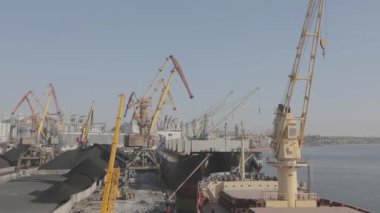 Hızla gemiden vinçlerle kömür boşaltılıyor. Gemi limandaki vinçlerle boşaltıldı. Ukrayna limanında gemiler.
