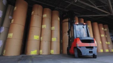 Forklift büyük bir rulo kağıt taşıyor. Bir forklift fabrikada kağıt taşıyor. Duvar kağıdı fabrikasında yükleyici.