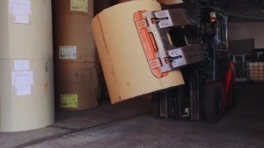 Forklift büyük bir rulo kağıt taşıyor. Bir forklift fabrikada kağıt taşıyor. Duvar kağıdı fabrikasında yükleyici.