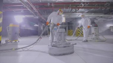 İnşaatçılar zemini özel ekipmanlarla cilalıyorlar. Beton yüzey öğütme. İnşaat alanında inşaatçılar.