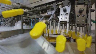 Ice cream is dipped into a container with fruit glaze. Colorful bright ice cream on the conveyor. Ice cream production.