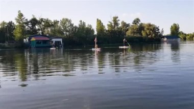 Girls do sports exercises on the sup board. Physical exercises on the sup board. Sports recreation on the river. Water sports.