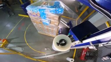 Plastik film kutularını paketliyorum. Kutu germe ambalaj makinesi. Palet ambalaj makinesi. Kutuları bir çemberde plastik bir filme sarmak için makine..