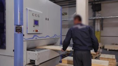 A man works at a sawmill, a workflow at a modern sawmill. Industrial interior woodworking factory.
