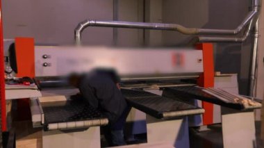 Bir adam, bir mobilya fabrikasında, endüstriyel iç mekanda makine için çalışıyor..