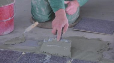 The builder lays tiles on the cement mortar. Construction worker laying tiles on the floor for mortar.