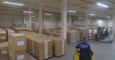 Fabrikada bitmiş ürünlerle dolu büyük bir depo. Fabrikada kutularla dolu bir depo. Büyük bir depodaki bir forklift kutuları taşır..
