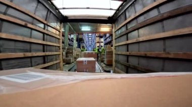 Mallar kamyondan boşaltılıyor. Malları kamyondan boşaltma işlemi. İşçiler kamyonu boşaltıyor. Modern depo.