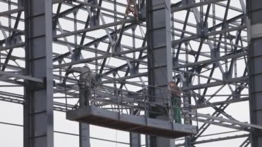 İşçiler metal yapılar boyuyor. İnşaat işi. Endüstriyel dış görünüş. İnşaatçılar binanın metal yapısını un ufak ediyorlar..