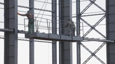 İşçiler metal yapılar boyuyor. İnşaat işi. Endüstriyel dış görünüş. İnşaatçılar binanın metal yapısını un ufak ediyorlar..