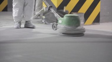 Processing a concrete floor with a grinder close-up. Grinding concrete floor large plan. Construction site equipment close-up.