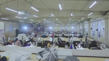Birçok terzi bir giyim fabrikasında çalışır. Bir giyim fabrikasında çalışma süreci. Büyük dikiş atölyesi. Terziler fabrikada ürün yapar. Kumaş fabrikası.