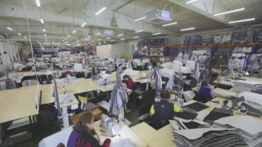 Birçok terzi bir giyim fabrikasında çalışır. Bir giyim fabrikasında çalışma süreci. Büyük dikiş atölyesi. Terziler fabrikada ürün yapar. Kumaş fabrikası.