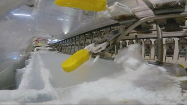 Ice cream is dipped into a container with fruit glaze. Colorful bright ice cream on the conveyor. Ice cream production.