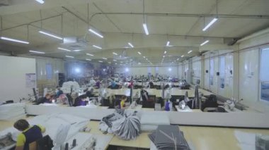 Birçok terzi bir giyim fabrikasında çalışır. Bir giyim fabrikasında çalışma süreci. Büyük dikiş atölyesi. Terziler fabrikada ürün yapar. Kumaş fabrikası.