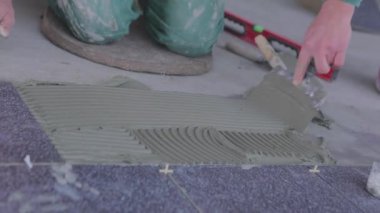 The builder lays tiles on the cement mortar. Construction worker laying tiles on the floor for mortar.