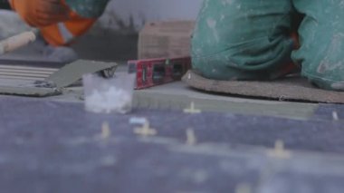 The builder lays tiles on the cement mortar. Construction worker laying tiles on the floor for mortar.