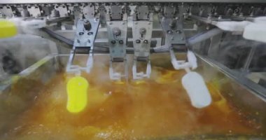 Ice cream is dipped into a container with fruit glaze. Colorful bright ice cream on the conveyor. Ice cream production.