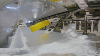 Ice cream is dipped into a container with fruit glaze. Colorful bright ice cream on the conveyor. Ice cream production.