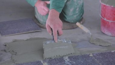 The builder lays tiles on the cement mortar. Construction worker laying tiles on the floor for mortar.