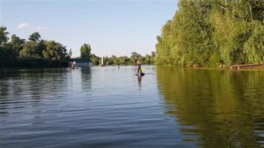 Girls do sports exercises on the sup board. Physical exercises on the sup board. Sports recreation on the river. Water sports.