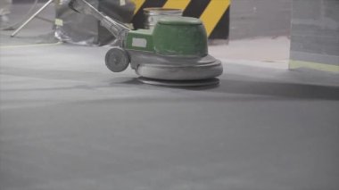 Processing a concrete floor with a grinder close-up. Grinding concrete floor large plan. Construction site equipment close-up.