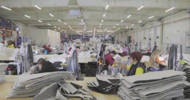 Birçok terzi bir giyim fabrikasında çalışır. Bir giyim fabrikasında çalışma süreci. Büyük dikiş atölyesi. Terziler fabrikada ürün yapar. Kumaş fabrikası.