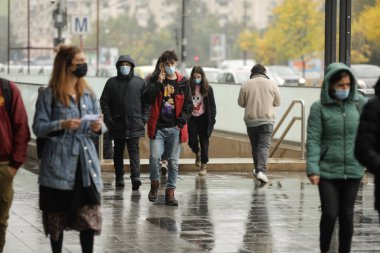 Bükreş, Romanya - 13 Ekim 2021: Covid-19 salgınında insanlar maskelerini yağmurlu sonbahar günlerinde takıyorlar.
