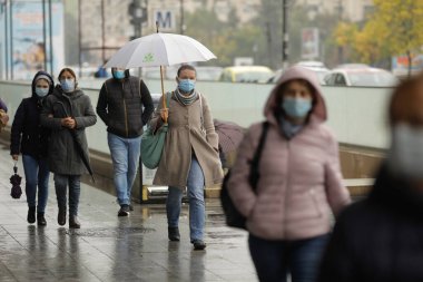 Bükreş, Romanya - 13 Ekim 2021: Covid-19 salgınında insanlar maskelerini yağmurlu sonbahar günlerinde takıyorlar.