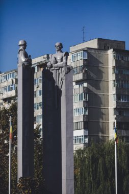 Bükreş, Romanya - 27 Ekim 2021: Komünist / Sovyet tarzı heykel, arka planda, Meçhul Asker 'in Bilinmeyen Kahraman / Mezarı Anıtı' ndaki apartman blokları olan askerleri resmediyor.