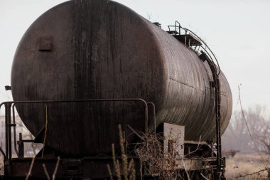 Güneşli bir kış gününde, bir tarlanın ortasında eski ve paslı demiryolu petrol tankeri ile sığ alan derinliği (seçici odak) görüntüsü.