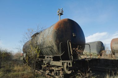 Güneşli bir kış gününde, bir tarlanın ortasında eski ve paslı demiryolu petrol tankeri ile sığ alan derinliği (seçici odak) görüntüsü.