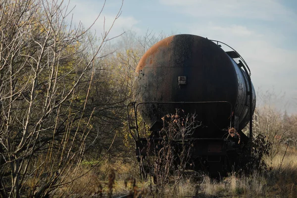 Güneşli bir kış gününde, bir tarlanın ortasında eski ve paslı demiryolu petrol tankeri ile sığ alan derinliği (seçici odak) görüntüsü.