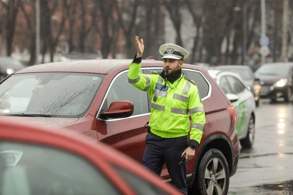 ルーマニアのブカレスト 2021年12月17日 ルーマニアの道路警察官は 雨の冬の日に忙しい交差点でトラフィックを管理します — ストック写真