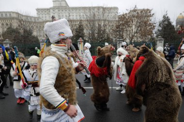 Bükreş, Romanya - 21 Aralık 2021: Bir grup insan ayı kürkü giyiyor ve Parlamento Sarayı önünde geleneksel Romanya ayinlerini (Bears Dance veya Dansul Ursilor) gerçekleştiriyor.